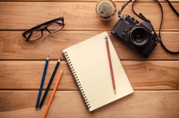 istock camera, notebook,pencil and eyeglasses on wood table 680898640