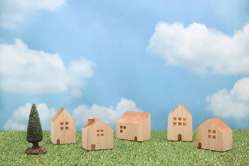 Houses on green grass over blue sky and clouds. Mortgage concept.