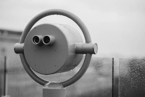 closeup coin operated binoculars overlooking after rain, white and black.