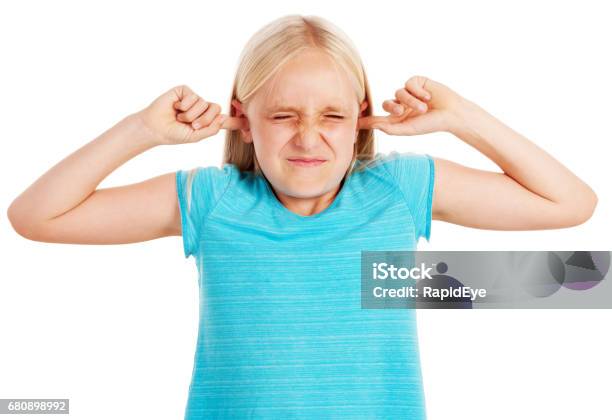 Little Blonde Girl Grimacing And Blocking Her Ears Stock Photo - Download Image Now - Fingers in Ears, Hands Covering Ears, Child