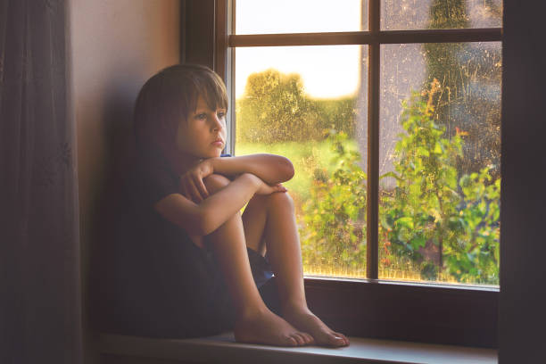 istock Sad child, boy, sitting on a window shield, watching the sunset 680902026