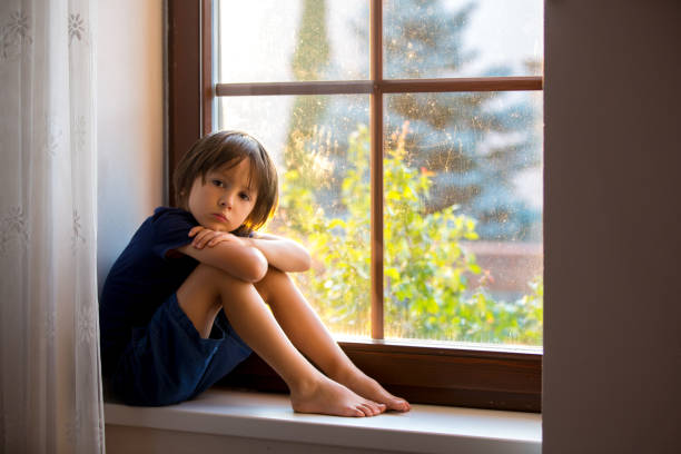 istock Sad child, boy, sitting on a window shield, watching the sunset 680902130