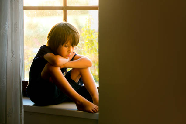 istock Sad child, boy, sitting on a window shield, watching the sunset 680902206