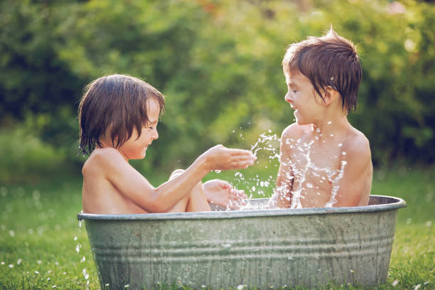 istock Two children, boy brothers, having a bath outdoors, making soap bubbles, summertime 680902488
