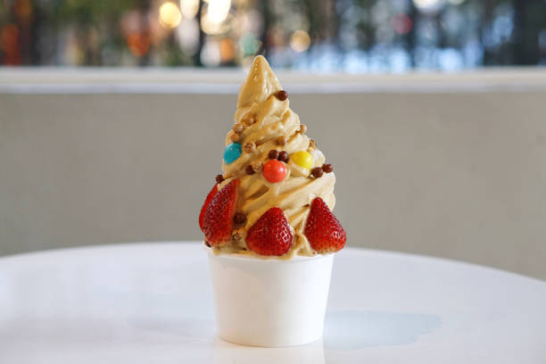 copa de primer plano de helado de yogur congelado orgánico, pecana de caramelo salado con fresa fresca y caramelo de chocolate en una comida plástica sobre fondo borroso. - yogur helado fotografías e imágenes de stock