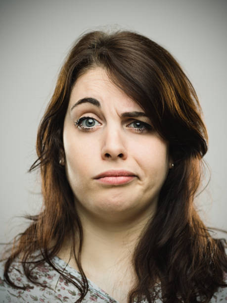 mujer joven molesta contra fondo gris - raised eyebrows fotografías e imágenes de stock