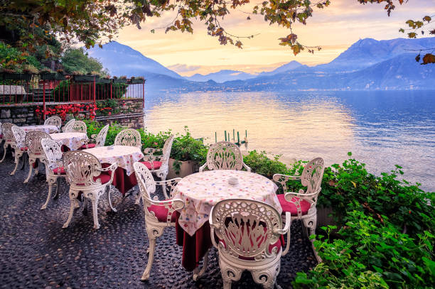 Lake Como and Alps Mountains on sunset, Italy Tables in a small cafe at the waterfront of Lake Como, Italy, with panorama of the Alps Mountains in background on sunset como italy photos stock pictures, royalty-free photos & images