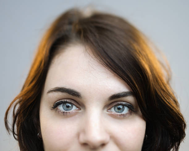 Beautiful gray eyes of a woman Close up of young caucasian woman with beautiful eyes against gray background. Horizontal shot of real woman in studio with sharp focus on eyes. Photography from a DSLR camera. tilt shift stock pictures, royalty-free photos & images