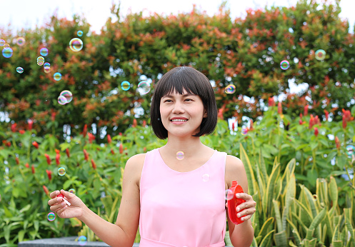 Young asian woman playing bubble on the roof top of building.