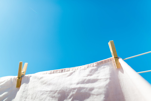 Bed sheet drying on a rope outside. The weather is beautiful and sunny with blue sky.