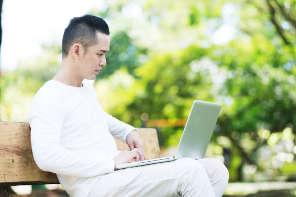istock Asian Man Sitting on a Bench with a Laptop. 680958442