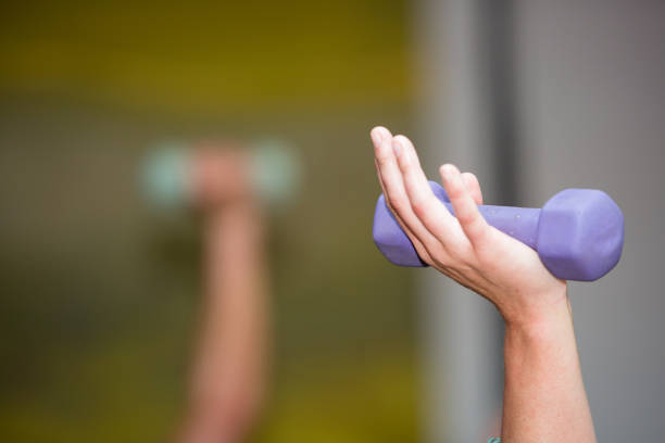 Close up of a hand holding a purple dumbbell