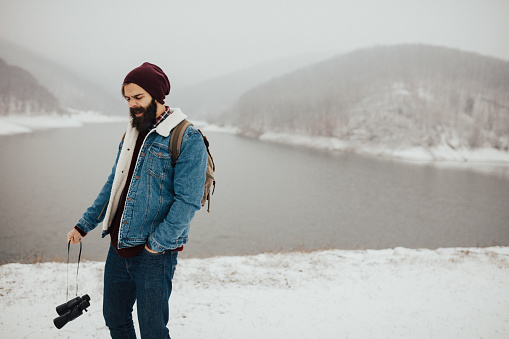 Bearded man sneezes outdoors on a cold winter day