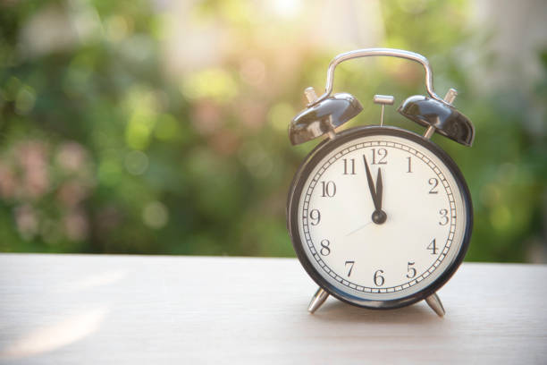 istock black alarm clock on table at morning in garden background. 681021720