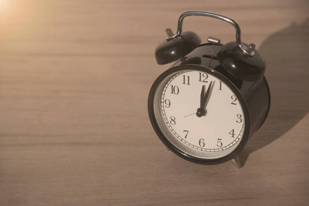 istock black alarm clock on wood table at morning. 681021738