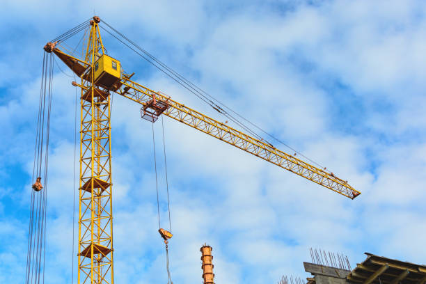 istock Yellow construction cranes and unfinished building with metal-concrete structure on a background of blue sky with white clouds 681063308