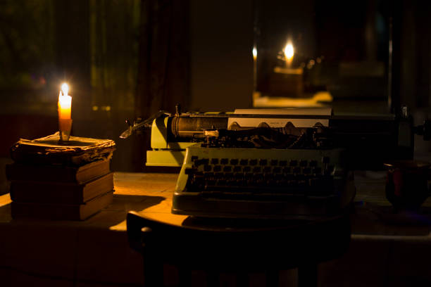 old typewriter at night with low light old typewriter at night with light from candle typewriter writing retro revival work tool stock pictures, royalty-free photos & images