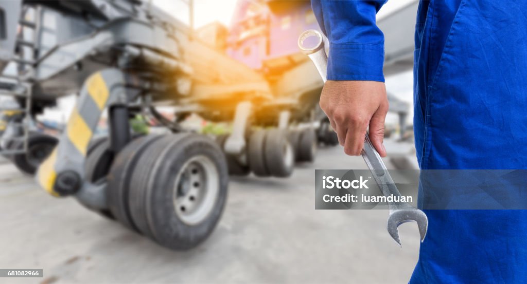 The mechanic with the arms of the cross with a large crane wheel at harbour is background. Truck Stock Photo