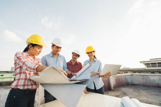 Multiethnic diverse group of engineers or business partners at construction site, working together on building's blueprint, architect industry or teamwork concept