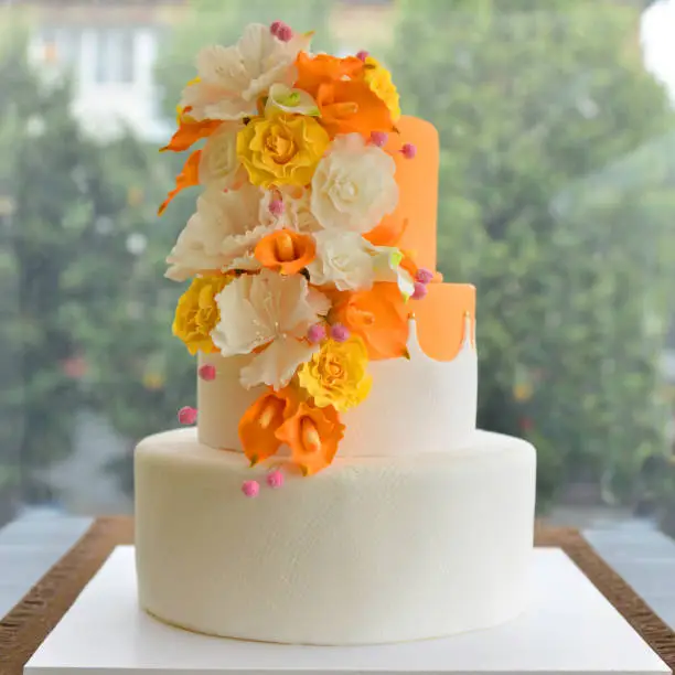 Photo of Wedding cake with flowers by the window