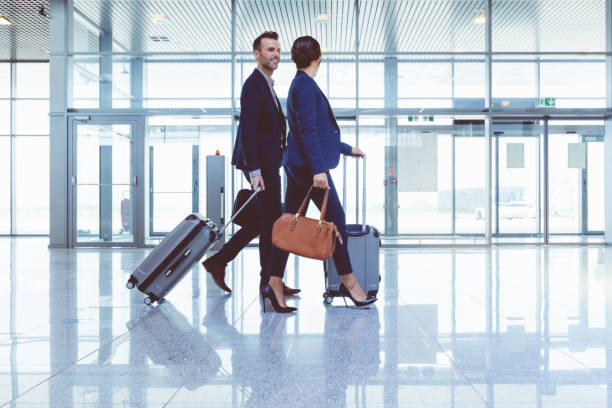 businesspeople walking with luggage inside airport terminal - travel airport business people traveling imagens e fotografias de stock