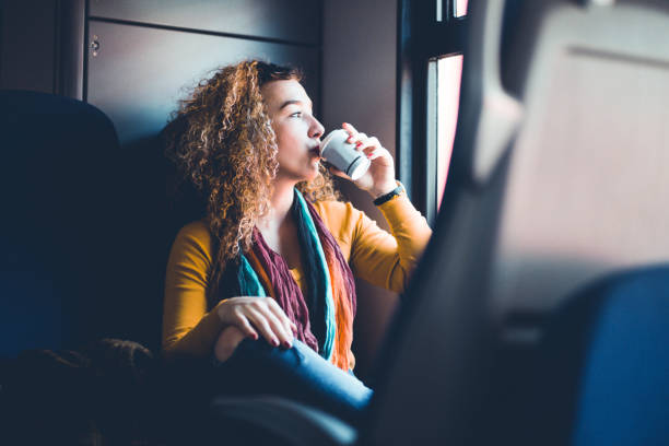 Girl Drinking CoffeeWhile Commuting By Train Attractive Curly-haired Girl Traveling By Train And Drinking First Morning Coffee. commuter train photos stock pictures, royalty-free photos & images