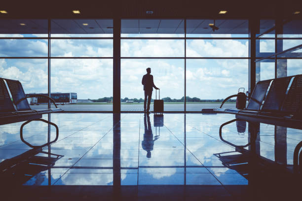 Business man waiting to board a flight in airport Silhouette of a business man with luggage waiting to board a flight in airport silhouette lounge stock pictures, royalty-free photos & images