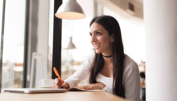 istock Young woman writing in her notebook and drinking morning coffee 681169906