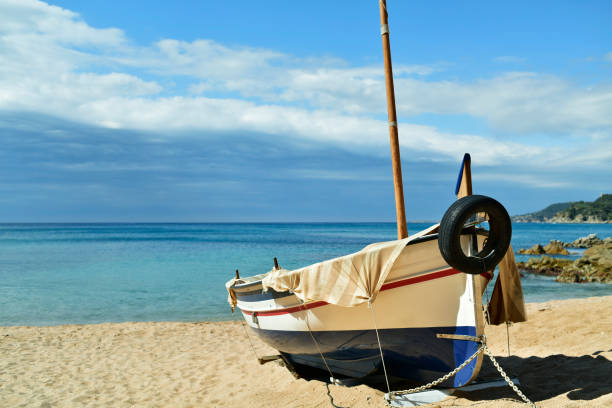 an old fishing boat stranded in the quiet beach Platja de Sa Caleta in Lloret de Mar, in the Costa Brava, Spain