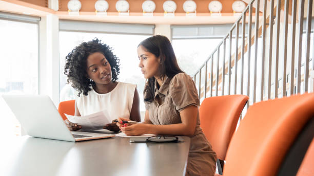 istock Two businesswomen using laptop in modern office with pensive expressions 681179074