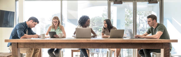 creative business professionals working on laptops in coworking space - hot desking imagens e fotografias de stock