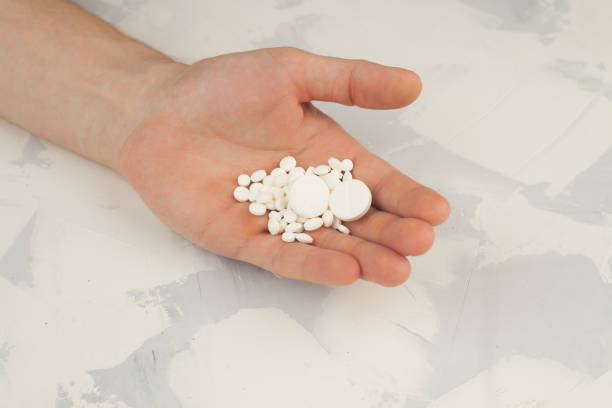 istock white round pills on hand, close up 681184098