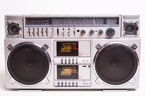 Vintage boom box from the 1980s with a radio and cassette player. Shot against a vintage woodgrain wall with copy space.