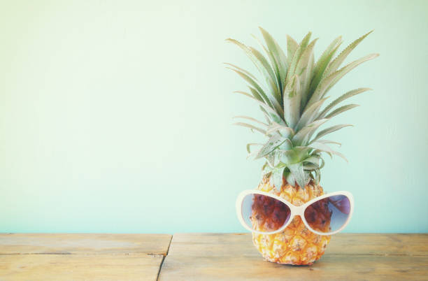istock Pineapple with sunglasses on the table. Beach and tropical theme. 681215770