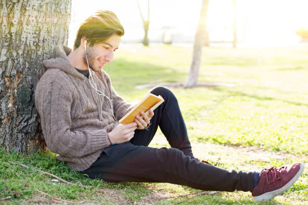 istock Young man reading book in the park 681229982