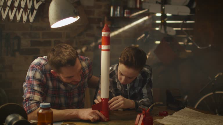 Father and son are modeling a toy rocket in a garage at home.