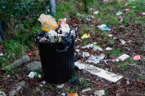 Chester, England, UK - March 11, 2017: The photo shows a overflowing litter bin, which is filled with rubbish to the top and rubbish, which has fallen out of the full garbage bin or which has been dumped on the floor. The photo was taken outdoors.