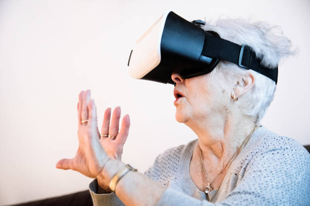 istock Mobility challenged senior woman enjoying VR helmet on her couch 681250128