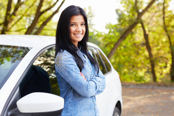 istock Smiling woman standing and leaning on car 681257480