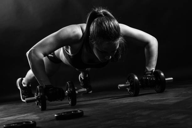 istock Woman bodybuilder lifting dumbbell isolated over black background, Black and white. 681265846
