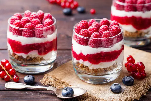 Photo of Raspberry dessert, cheesecake, trifle, mouse in a glass on a wooden background