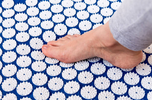 Treatment of foot. Massage mat with needles to treat the feet, fatigue, relaxation acupuncture mat stock pictures, royalty-free photos & images