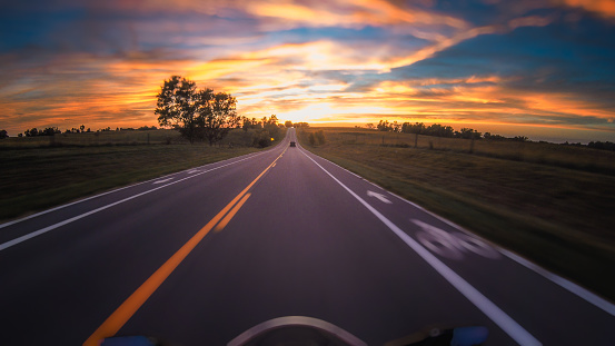 Motorycle speeding down highway toward the sunset