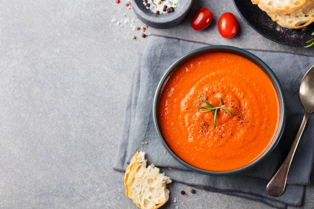istock Tomato soup in a black bowl on grey stone background. Top view. Copy space. 681288392