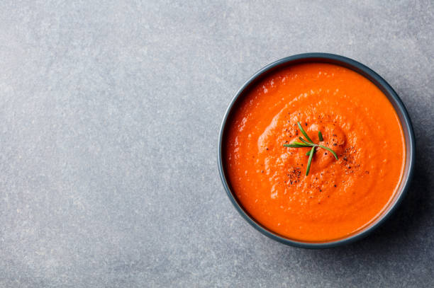 istock Tomato soup in a black bowl on grey stone background. Top view. Copy space 681292354