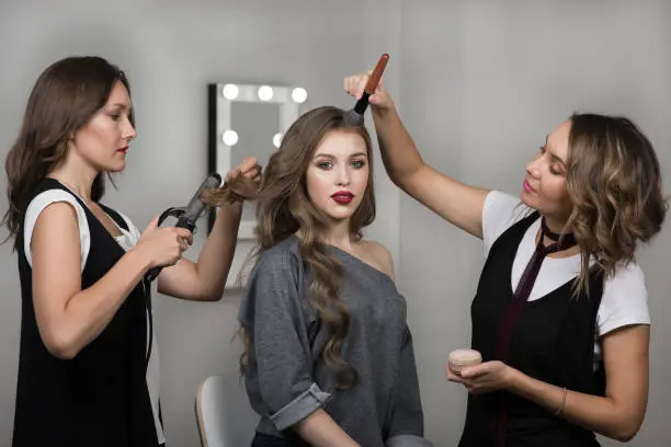 Photo of Makeup artist, hairstylist and model in beauty studio