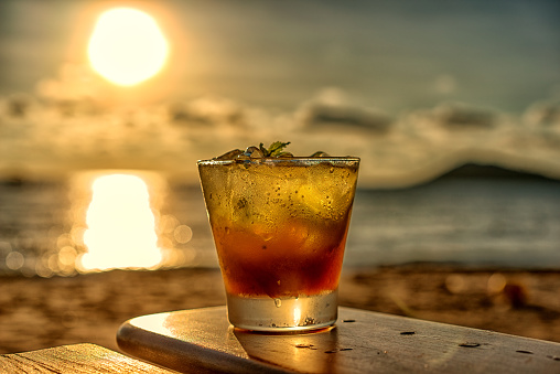The frozen glass of Mojito cocktail​ on the beach at sunset with blurred background.