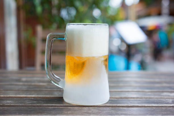 The Frozen mug of cold light beer at the pub wooden table, close up The Frozen mug of cold light beer at the pub wooden table, close up frost on glass stock pictures, royalty-free photos & images