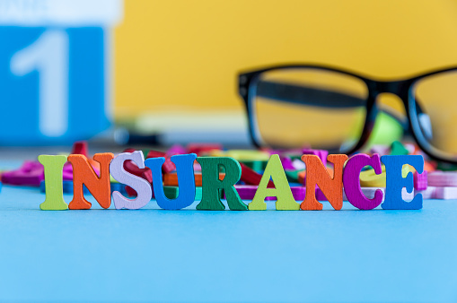 Insurance - word composed of small colored letters on business workplace of broker. Illustration of the concept of insurance.