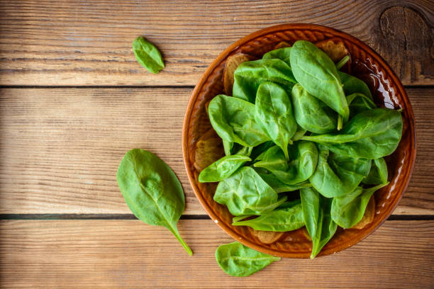 istock Fresh spinach leaves in bowl on rustic wooden table. 681355412